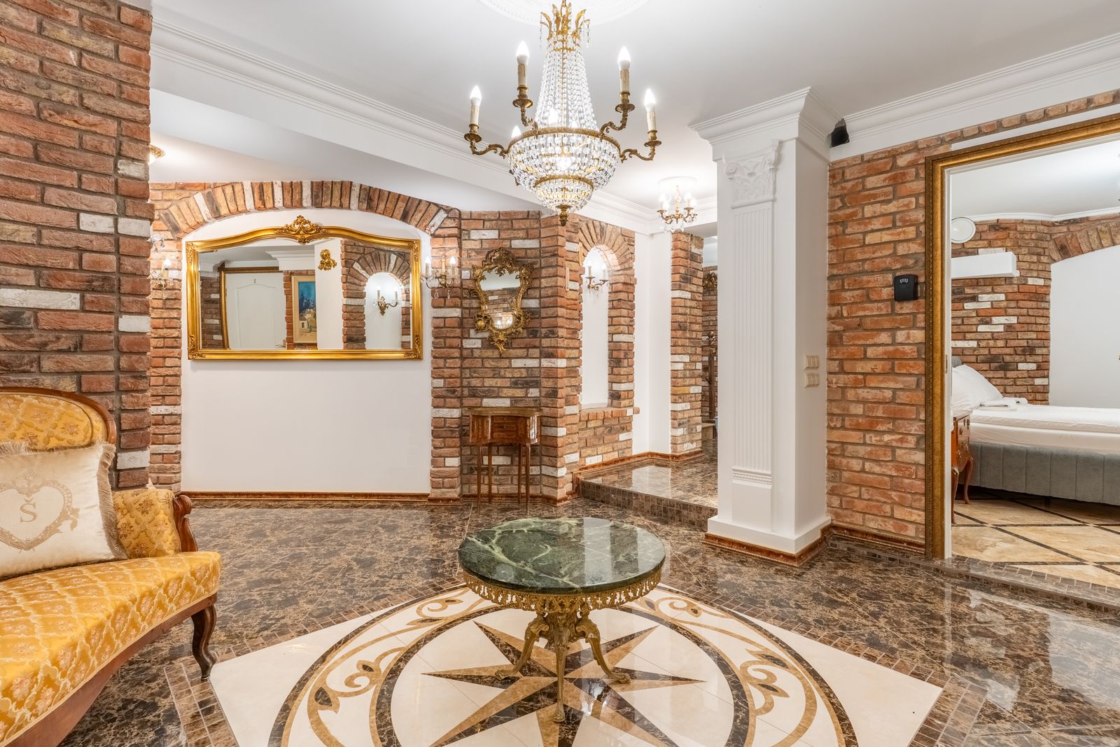 Hall with a crystal chandelier, gilded mirror and marble compass-rose floor beneath brick vaults — Underground Kingdom, Kaunas